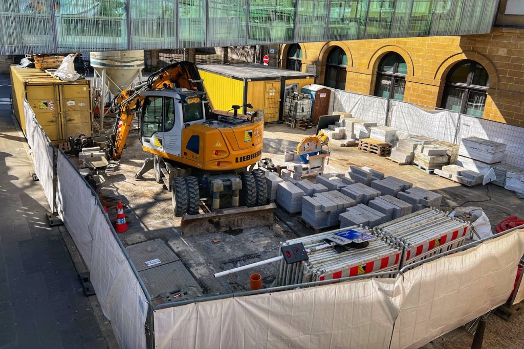 A construction site with machinery and materials in an urban setting during daytime.