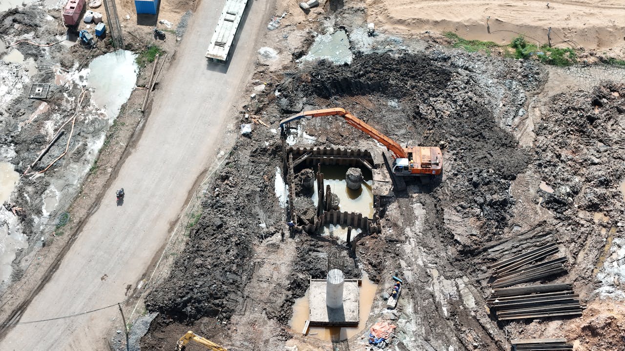 Top view of construction site showing an excavator working in muddy terrain.