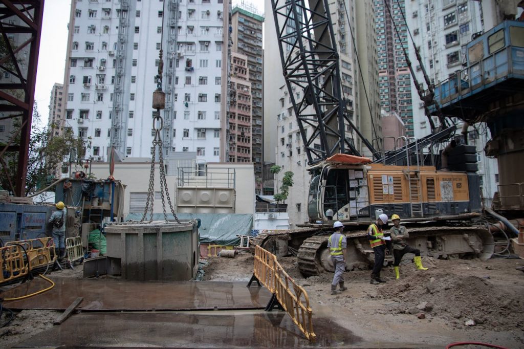 City construction site with workers, cranes, and high-rise buildings.