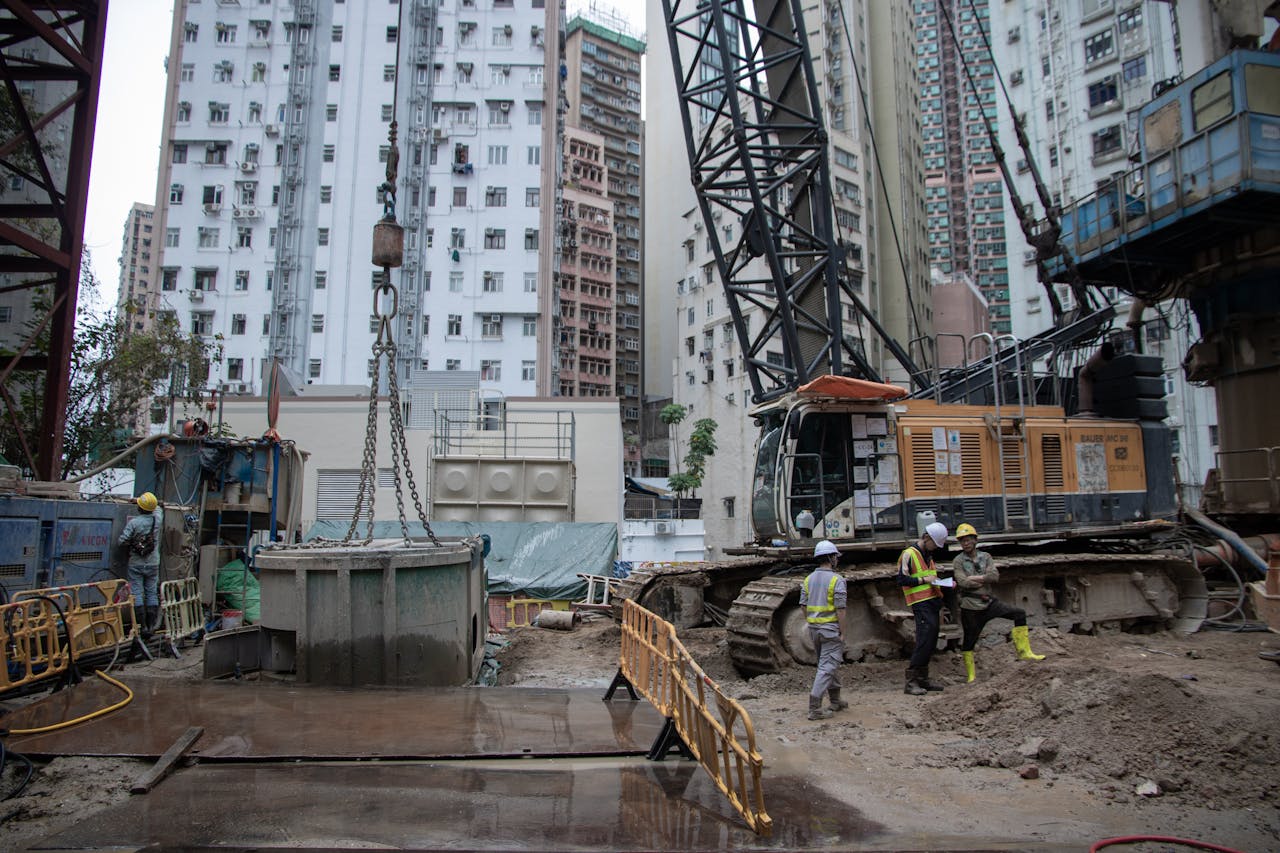 City construction site with workers, cranes, and high-rise buildings.